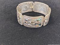 Front and side view of the sterling silver bracelet with abalone inlay showing floral motif, in good used condition.
