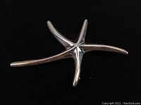 Front view of the starfish brooch showing the polished sterling silver finish and sculpted arms.
