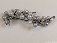 Front view of vintage Mikimoto silver brooch with 19 pearls arranged along branch design.