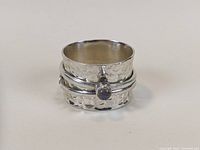 Wide sterling silver ring with moonstone and crescent moon detail from one side showing wide hammered band and spinner element with moonstone.