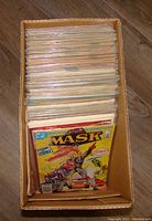 Cardboard box filled with over 100 plastic-sleeved comic books; M.A.S.K. #1 visible at front.