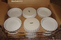 Photo of 6 white ceramic round crème brulee dishes in a cardboard box, showing fluted edges and smooth glaze.