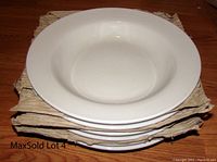 Stack of six cream-colored ceramic pasta bowls shown from the top and side, stacked with paper protection.