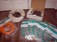 Multiple Ethernet cables in different colors including orange, green, and a large white coil cable, all new and some individually packaged.