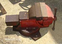Side view of red bench vise showing 6-inch jaws, solid heavy construction, and swivel base attached to ground.