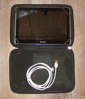 Samsung Galaxy Tab 2 SCH-1915 inside a black protective case with a white USB charging cable placed on it.