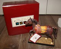 Photo showing the figurine standing on a wooden floor beside the original red collector's box with 'The Trail of Painted Ponies' text on the front.