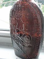 Close-up photo showing embossed locomotive and year 1885 on the deep amber bottle