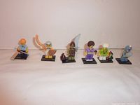Front view of six assorted Lego minifigures on black stands, showing detailed accessories and clothing