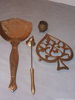 Four assorted brass items: heart-shaped pot holder trivet, candle snuffer, incense burner, hand mirror