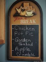 Full view of the chalkboard showing hand-written menu items and the coffee-themed carving above.