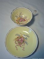 Top-down view of cup and saucer showing floral designs and "Mother" banner in cup interior.