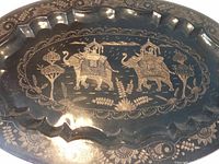 Close-up showing detailed incised elephant design and floral motifs on black lacquer brass tray.