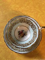 Top view of cup inside matching saucer showing central floral pattern and gold detailed edging on pale blue band.