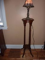 View of the carved wood stand with a lamp on top, showing overall height and structure.