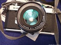 Camera front view showing the 55mm f/2 lens attached, with visible manufacturer markings on lens glass and barrel.