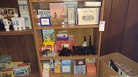 Shelf view showing various Avon boxes and collectible bottles including a train and car decorative items.
