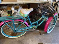 Side view of Schwinn Del Mar beach cruiser bicycle showing teal frame, pink fenders, and floral patterned seat with rear cargo rack.