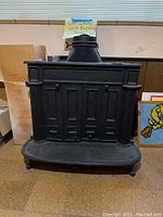 Front view of the black cast iron wood-burning stove showing decorative paneling and fluted side columns.