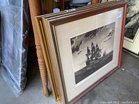 Four large framed and matted etchings stacked against a wooden chair, showing uniform size and frames with a visible price tag $40 each.