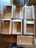 Seven original cardboard display boxes, each containing a silver coin in a plastic capsule.