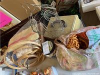Wide shot showing wire chicken-shaped basket, embroidery hoops, a bag with yarn and fabric pieces, and a yellowish fabric.