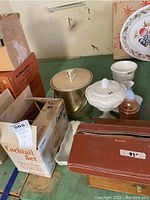 Wide view of vintage barware lot showing ice bucket, cocktail set box, milk glass items, and leather case on green surface.