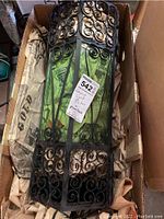 Full view of the vintage hanging light fixture inside a cardboard box, showing ornate metal scroll design and green glass panels.