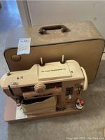 Vintage Singer 401A sewing machine and its beige carrying case on the floor, showing machine details such as knobs and spool holder.