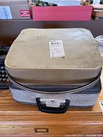 Two stacked vintage typewriter carrying cases with wear and scratches, showing labels and handles.