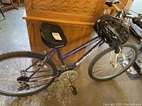 Side view of purple Roadmaster women's bicycle with black helmet resting on handlebar.