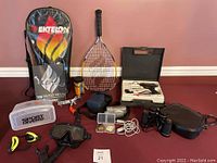 Full lot layout showing Ektelon racquetball set, Sport Divers goggles and mask with snorkel, Olympus camera, Tasco binoculars, and Weller soldering kit.