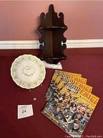 Photo showing antique 1912 calendar plate, wood corner shelf, four Flashback magazines, and 1935 tax token laid out on floor.