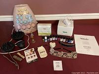 Full lot on red surface showing all items including curlers, diffuser attachments, perfume bottle, soaps, hair bands, trinket box, hair clip, embroidered headband, Welledia diffuser, and oils.