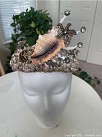 Front view of the mermaid seashell crown on foam head showing main conch shell and rhinestone starfish.