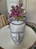 Front view of handmade seashell mermaid crown on foam head showing glittered purple and green petals and beads