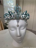 Front view of handmade seashell mermaid crown on foam mannequin head with turquoise and pearl decorations.