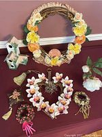 Full lot overview showing large grapevine wreath with yellow and peach flowers, small birdhouses, and multiple smaller wreaths and tassels arranged on flat surface.