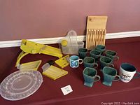 Kitchen Aid mandolin slicer assembly, blades, clear plastic storage case, deviled egg tray, mugs, wooden utensil holder