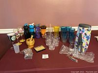 Wide shot showing all barware items together including cups, wine tote, mortar pestle, and picks on red table