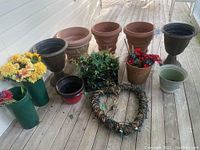 Photo showing six large planters in various colors and sizes, artificial flower bunches, small containers, and the grapevine heart wreath with lights laid on the floor.