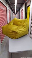 Side view of gold/yellow beanbag club chair on table in storage corridor