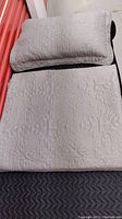 Gray coverlet and pillow sham laid out, showing overall condition and size