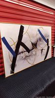 Painting showing full art with abstract black strokes, blue lines, gold circles on white canvas framed in gold frame
