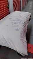 Photo showing full queen size comforter laid flat with visible silver floral embroidery at bottom.