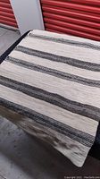 Full view of the black and off-white striped rug laid flat showing pattern and colors.