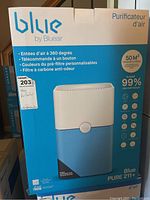 Front view of the Blueair Blue PURE 211+ air purifier box showing product image and features like 360-degree air intake, one-button remote control, customizable pre-filter colors, suitable for 50 square meters, and 99% particle elimination.