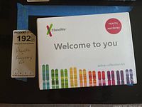 Front view of sealed 23andMe kit box with health and ancestry labeling and colorful chromosome graphics.