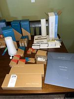 Top view of all SimplySafe components arranged on table showing base stations, keypads, motion and entry sensors, key fobs, power adapters, and signage boxes.