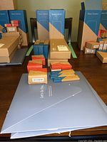 Multiple boxed SimpliSafe system components including three base stations, various smaller boxes likely for keypads, key fobs, sensors, and signage arranged on a table.